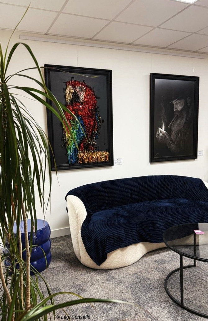 Espace d’attente avec canapé design bleu marine et œuvres d’art accrochées au mur dans les bureaux de Légi Conseils.