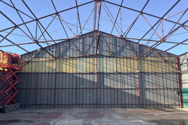 Bâtiment industriel existant avec charpente en acier et bardage métallique, avant réhabilitation.